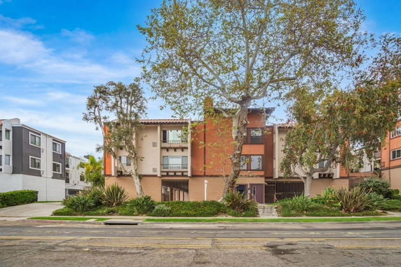 Front view of a multi-story residential building with trees in front.
