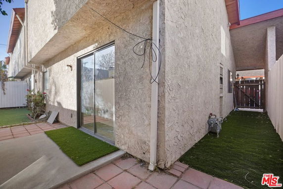 Side view of a house with stucco walls and sliding glass doors.