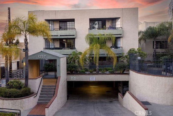 Front view of a multi-story residential building with balconies and a covered parking entrance.