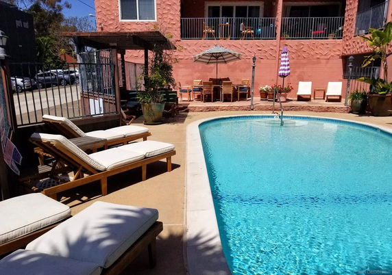 Outdoor swimming pool area with lounge chairs and table setting.