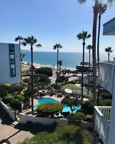 Panoramic view of a coastal area with a swimming pool, high-rise buildings, and the ocean in the background.