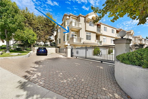 Front view of a multi-story residential building with balconies and a gated entrance.