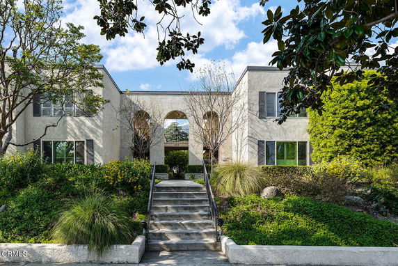 Front view of a two-story house with arched entrance and symmetrical design.