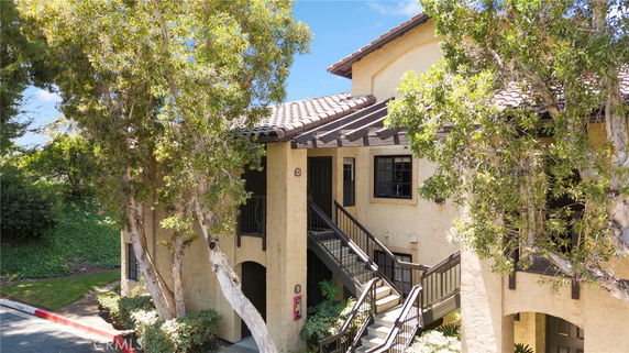 Front view of a two-story building with a stairway entrance and trees around.