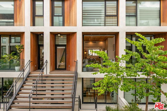 Front view of a modern multi-story building with large glass windows and wooden accents.