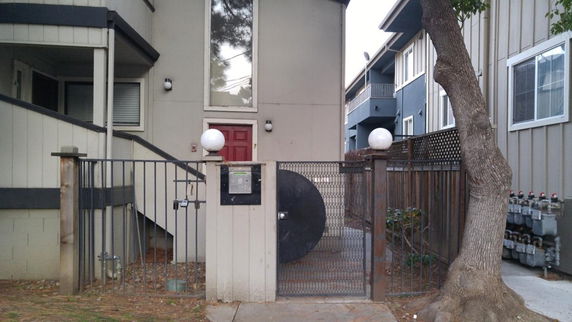 Front view of a house with a red door and a gated entrance.