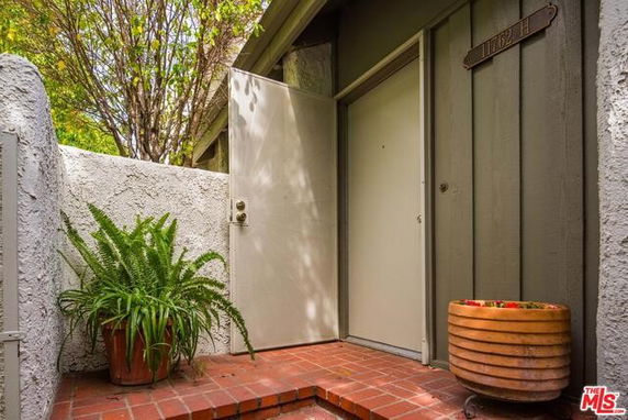Front view of a house entrance with plants and a brick pathway.