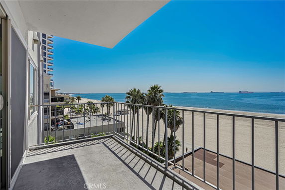 Balcony view overlooking a beach and ocean with nearby buildings.