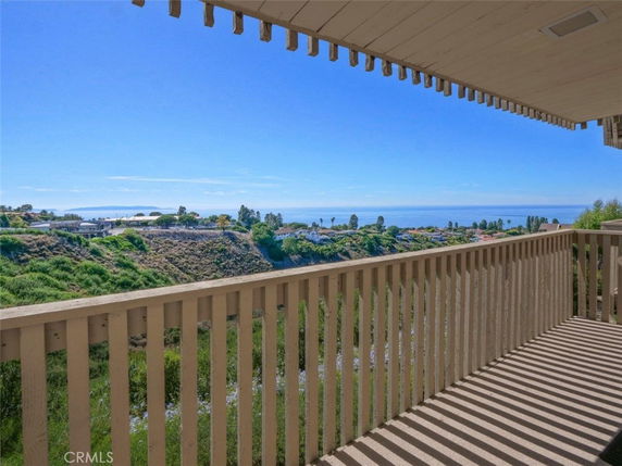 Balcony view overlooking a vast landscape with distant ocean and greenery.