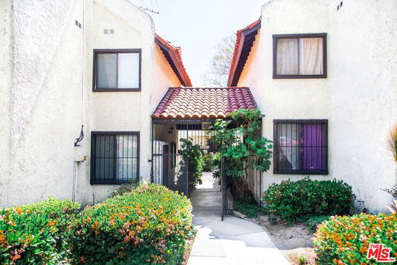 Front view of a two-story residential building with a tiled roof and gated entry.