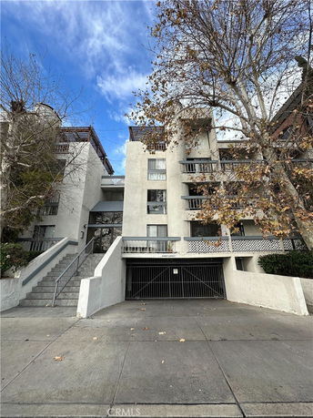 Front view of a multi-story residential building with a gated entrance and external staircase.