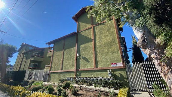 Front view of a multi-story building with green exterior walls and wooden beams.