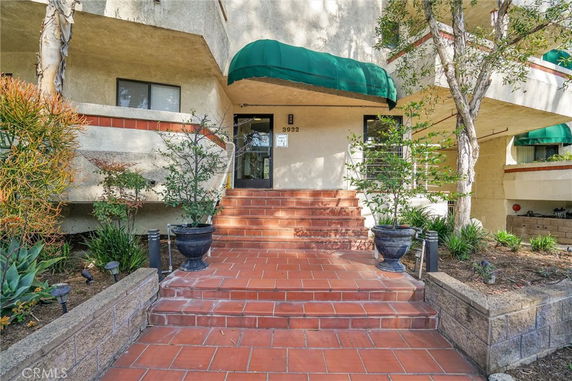 Front view of a building entrance with green awning and brick steps.