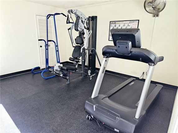 Room with fitness equipment including a treadmill and exercise machine.