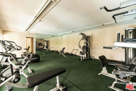 Room equipped with various gym exercise machines.