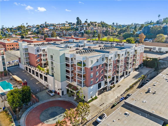 Aerial view of a multi-story residential building with balconies and a surrounding area.