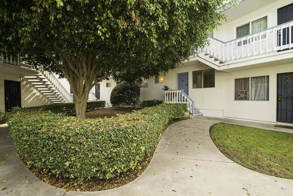 View of an apartment building exterior with pathways and greenery.