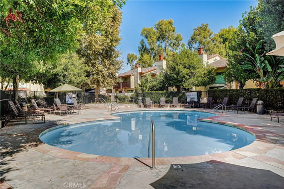 Outdoor swimming pool in a residential area with surrounding lounge chairs.