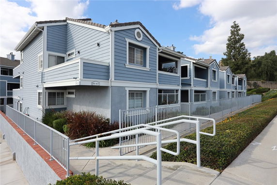Front view of a two-story blue townhouse complex with balconies and a ramp.