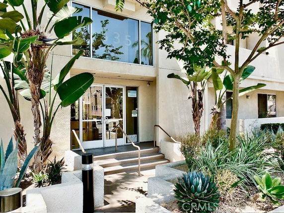 Front view of a multi-story building entrance with stairs and glass doors.