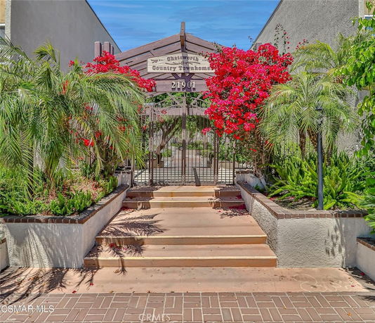 Front entrance of a townhouse with gated archway and surrounding plants.