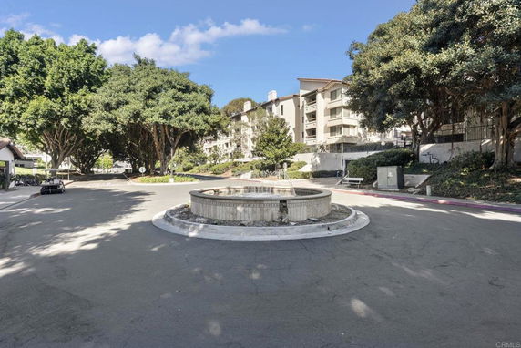 View of residential apartment buildings from the street with a central circular fountain.