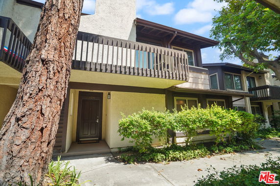 Front view of a two-story house with a balcony and a front door entrance.