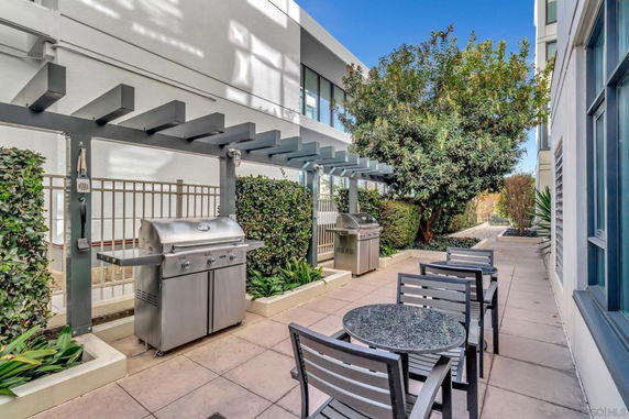 Outdoor area with barbecue grills and seating, adjacent to a modern building.