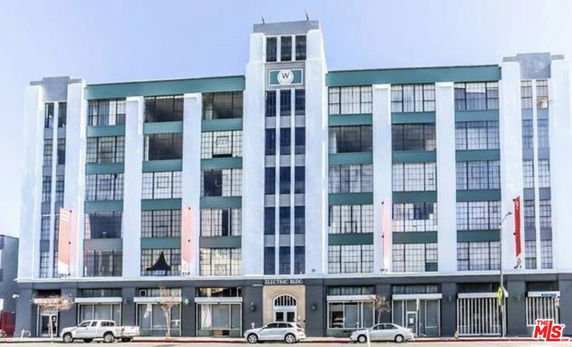 Front view of a multi-story building with large windows and vertical columns.