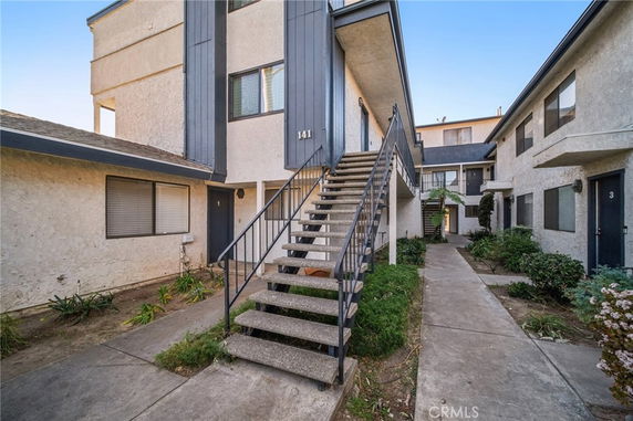 Front view of a two-story apartment building with external staircases and multiple units.