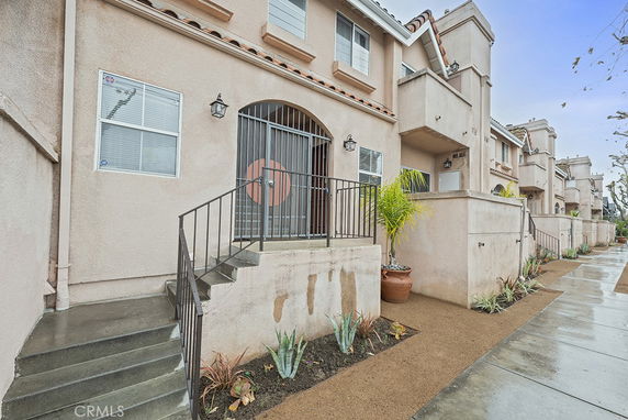 Front view of a multi-story building with entry steps and potted plants.