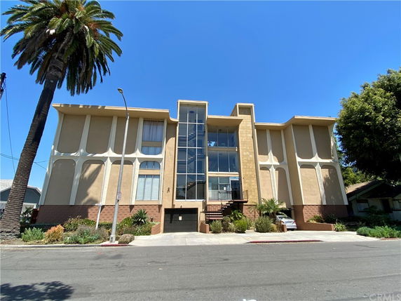 Front view of a multi-story building with a central glass section and beige walls.
