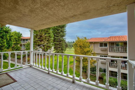 View from a covered balcony overlooking nearby residential buildings and greenery.