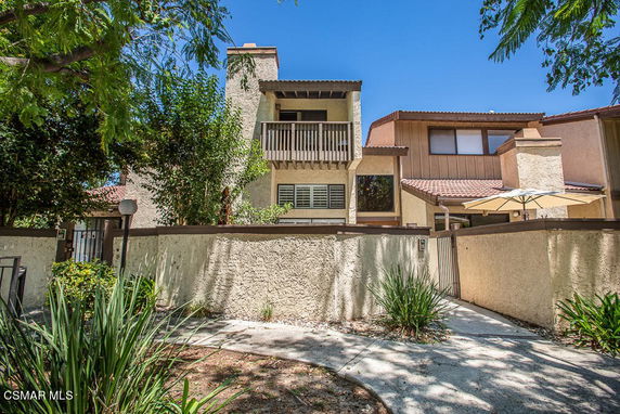 Front view of a multi-story building with balconies and a stucco exterior.