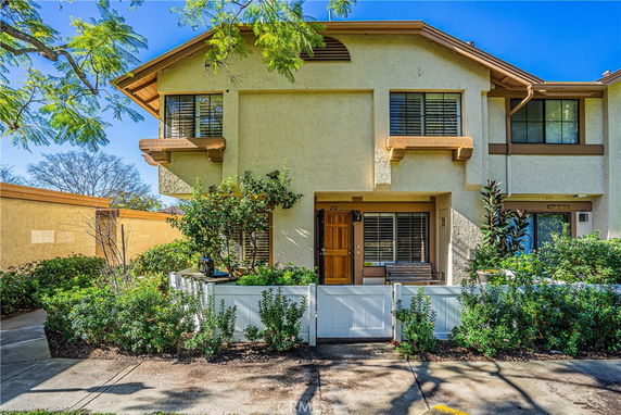Front view of a two-story townhouse with a small fenced garden area.