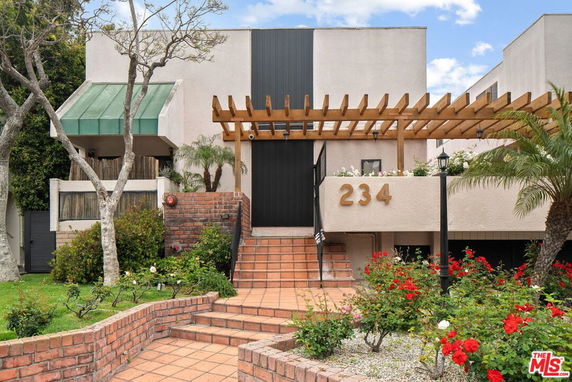 Front view of a multi-story building with a pergola and entrance steps.