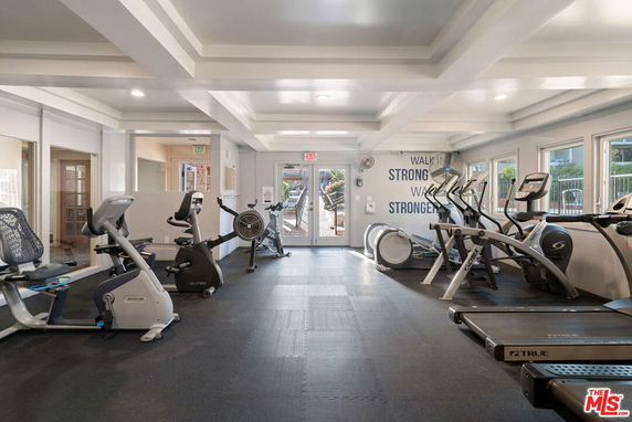 Room with gym equipment, including treadmills and exercise bikes, in a clubhouse.