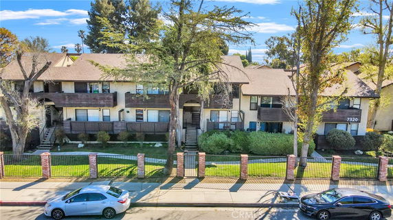 Front view of a two-story residential building with a fenced yard.