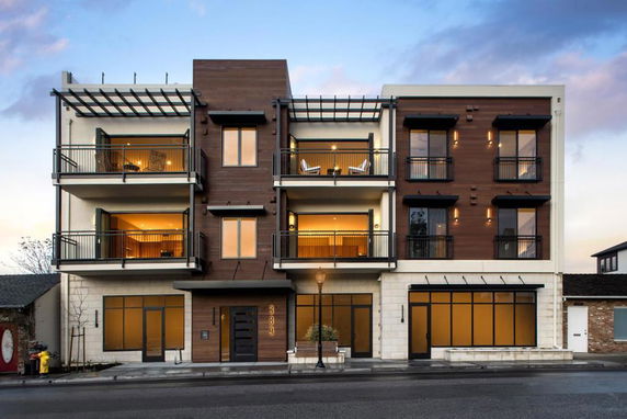 Front view of a modern multi-story building with balconies and large windows.