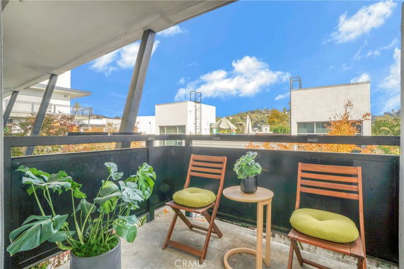 View from a balcony overlooking modern buildings and distant hills.