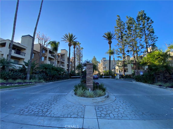Front view of an apartment complex with multiple stories and palm trees.