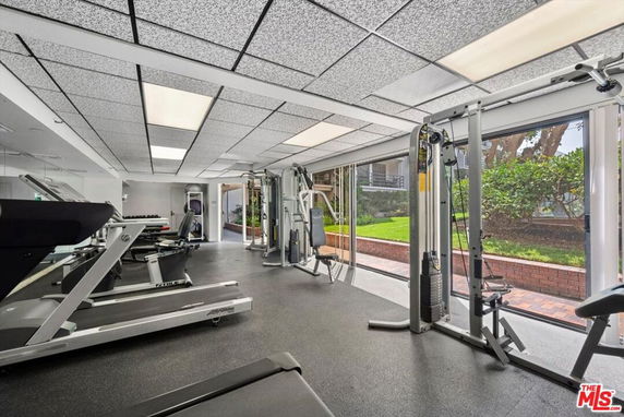 Indoor gym area with exercise equipment and large windows.