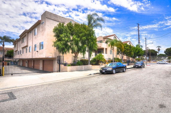 Front view of a multi-story residential building with gated parking.
