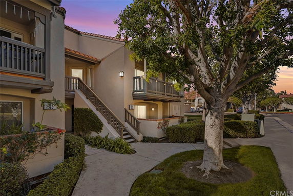 Front view of a two-story residential building with balconies and outdoor stairs.