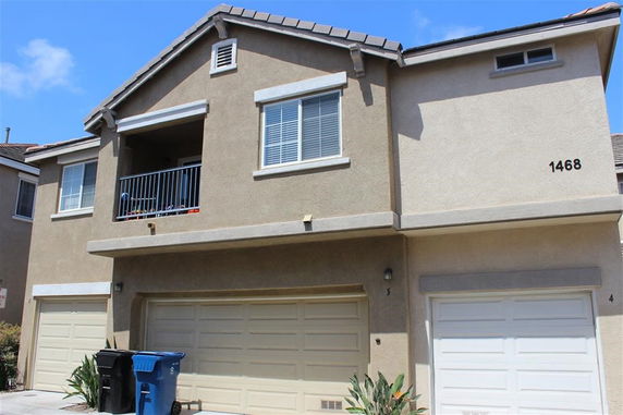 Front view of a two-story house with multiple garages and a balcony.
