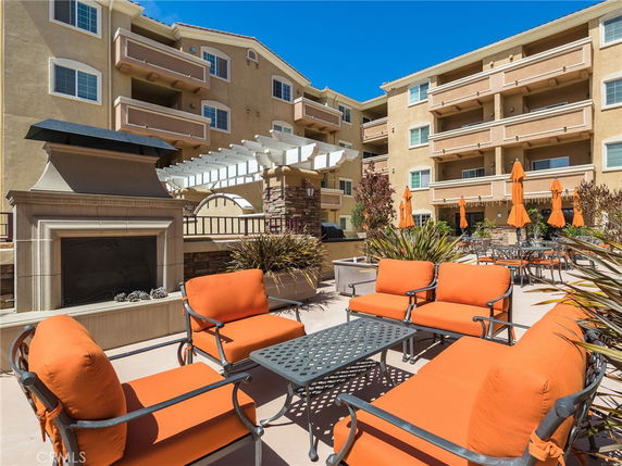 Front view of a multi-story residential building with balconies and outdoor seating area.