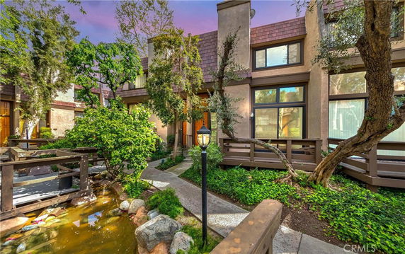 Front view of a multi-story house with a garden and pathway.