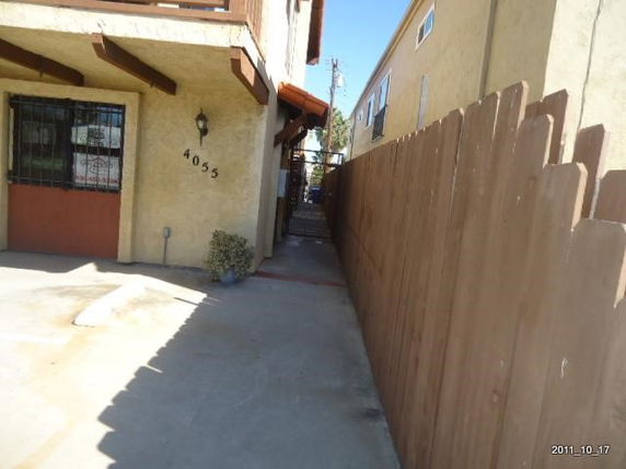 Front view of a two-story house with wooden fencing and concrete pathway.