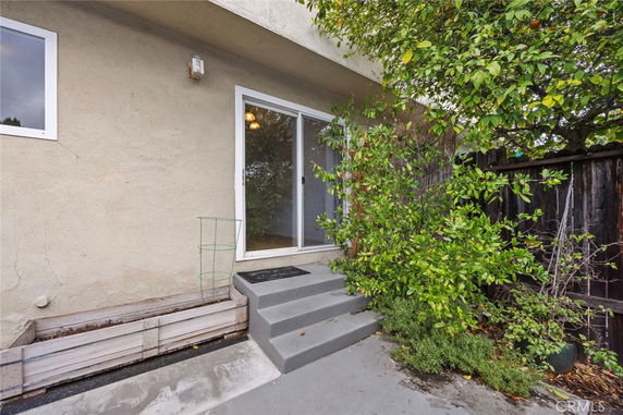 Back view of a house with sliding glass door and concrete steps.