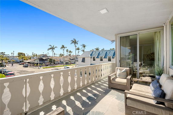 Balcony view overlooking residential area with palm trees and distant houses.